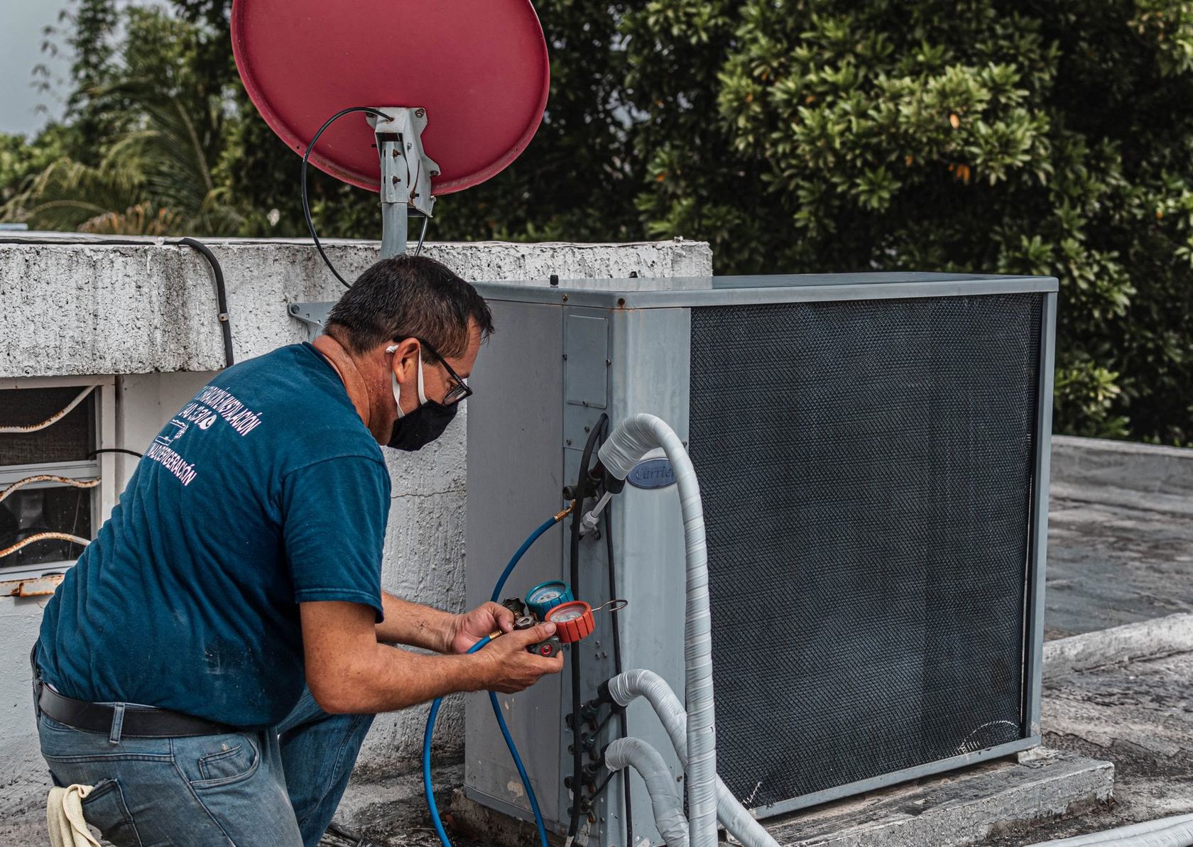 An HVAC technician checking refrigerant gauges on an outdoor condenser